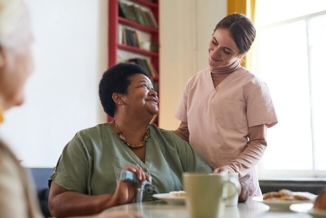 Portrait,Of,Smiling,Young,Woman,Assisting,Female,Patient,During,Dinner